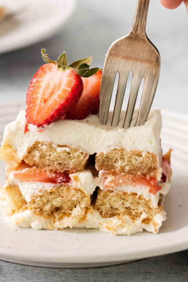 Slice of strawberry tiramisu on a plate with a fork.