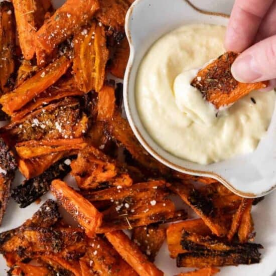 Parmesan smashed carrots on a plate with aioli dipping sauce.