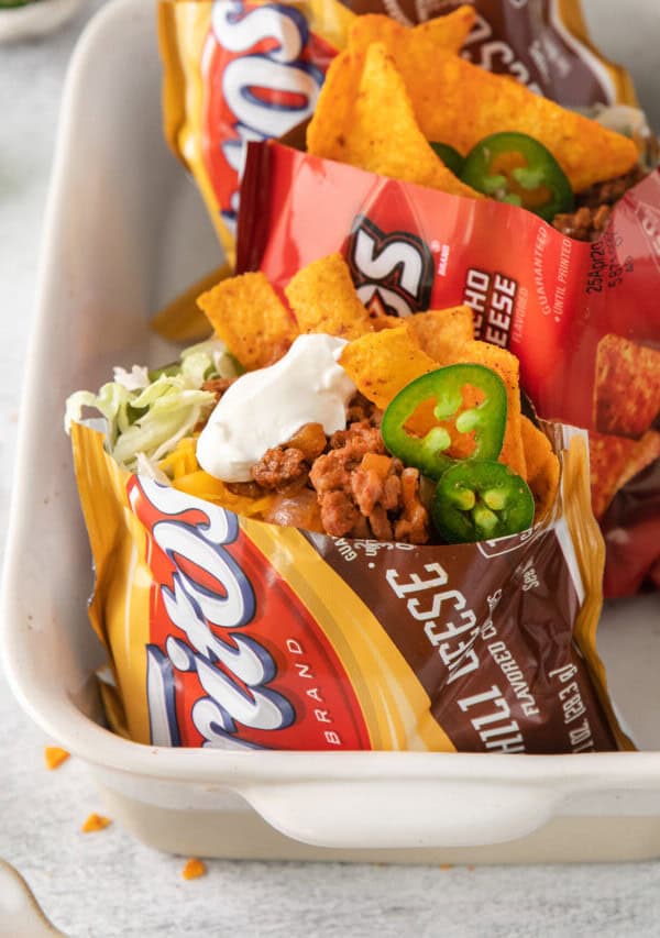 Walking tacos topped with sour cream.