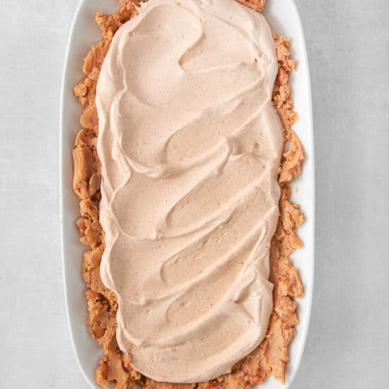 Seasoned sour cream on top of refried beans.