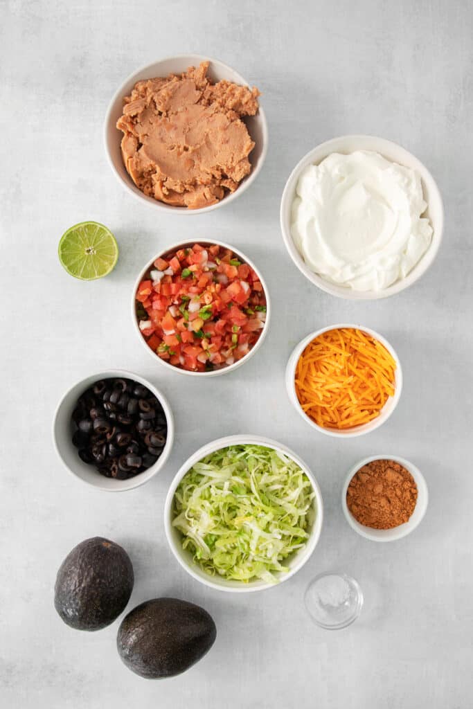 Ingredients for 7 layer taco dip in bowls.