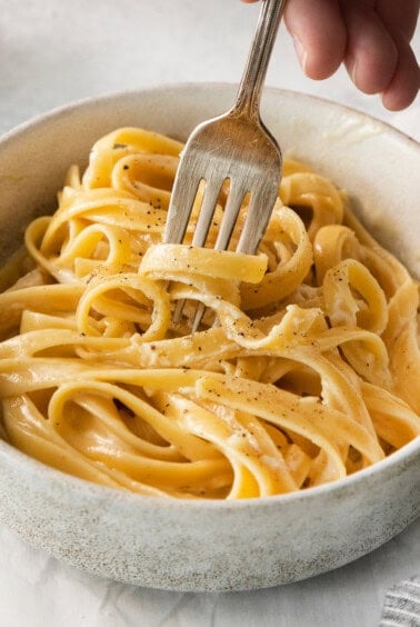 Homemade alfredo sauce over pasta in a bowl.