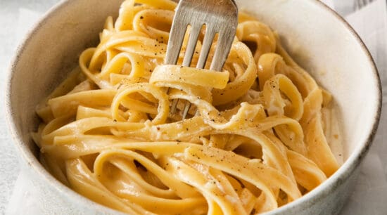 Homemade alfredo sauce over pasta in a bowl.