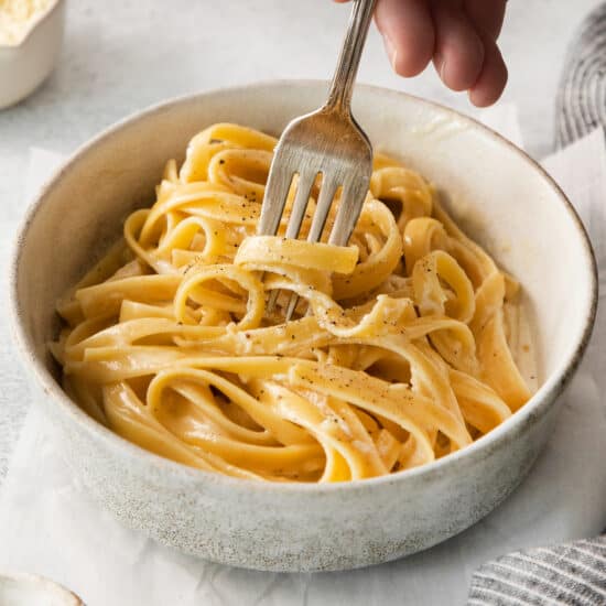 Homemade alfredo sauce over pasta in a bowl.