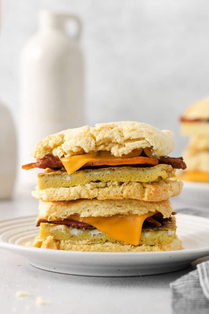 a stack of biscuits with cheese and bacon on a plate.