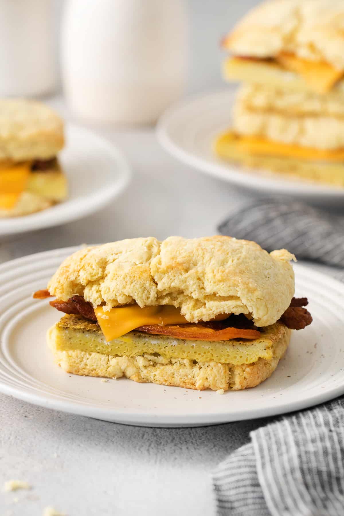 a stack of biscuits with bacon and cheese on a plate.