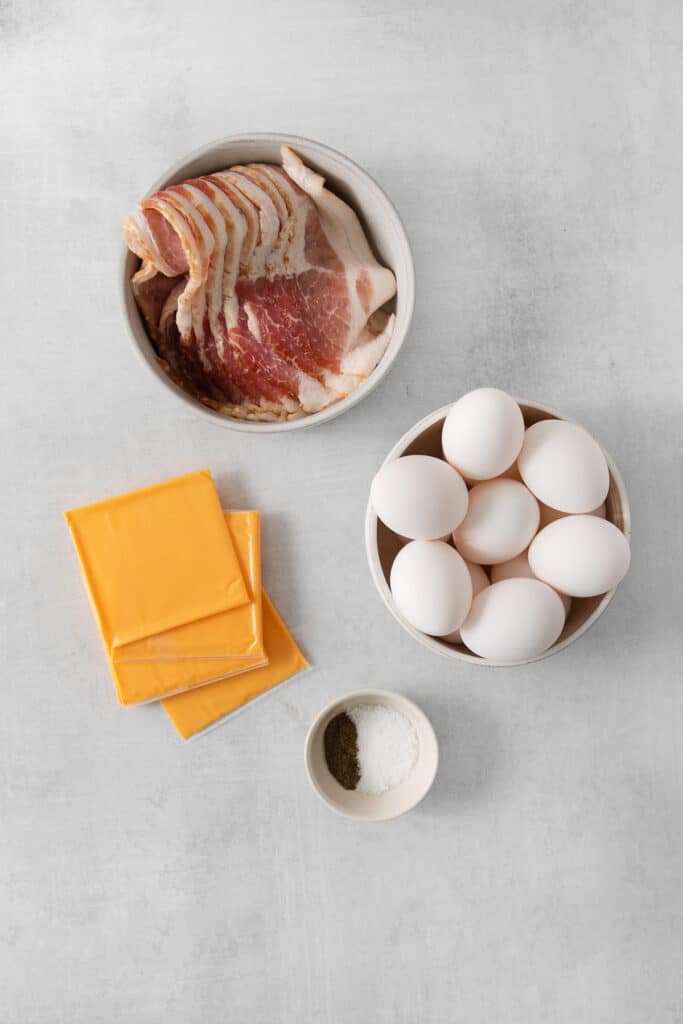 eggs, bacon, cheese and other ingredients on a table.