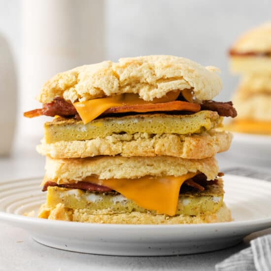 a stack of biscuits with bacon and cheese on a plate.