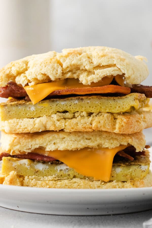 a stack of biscuits with bacon and cheese on a plate.