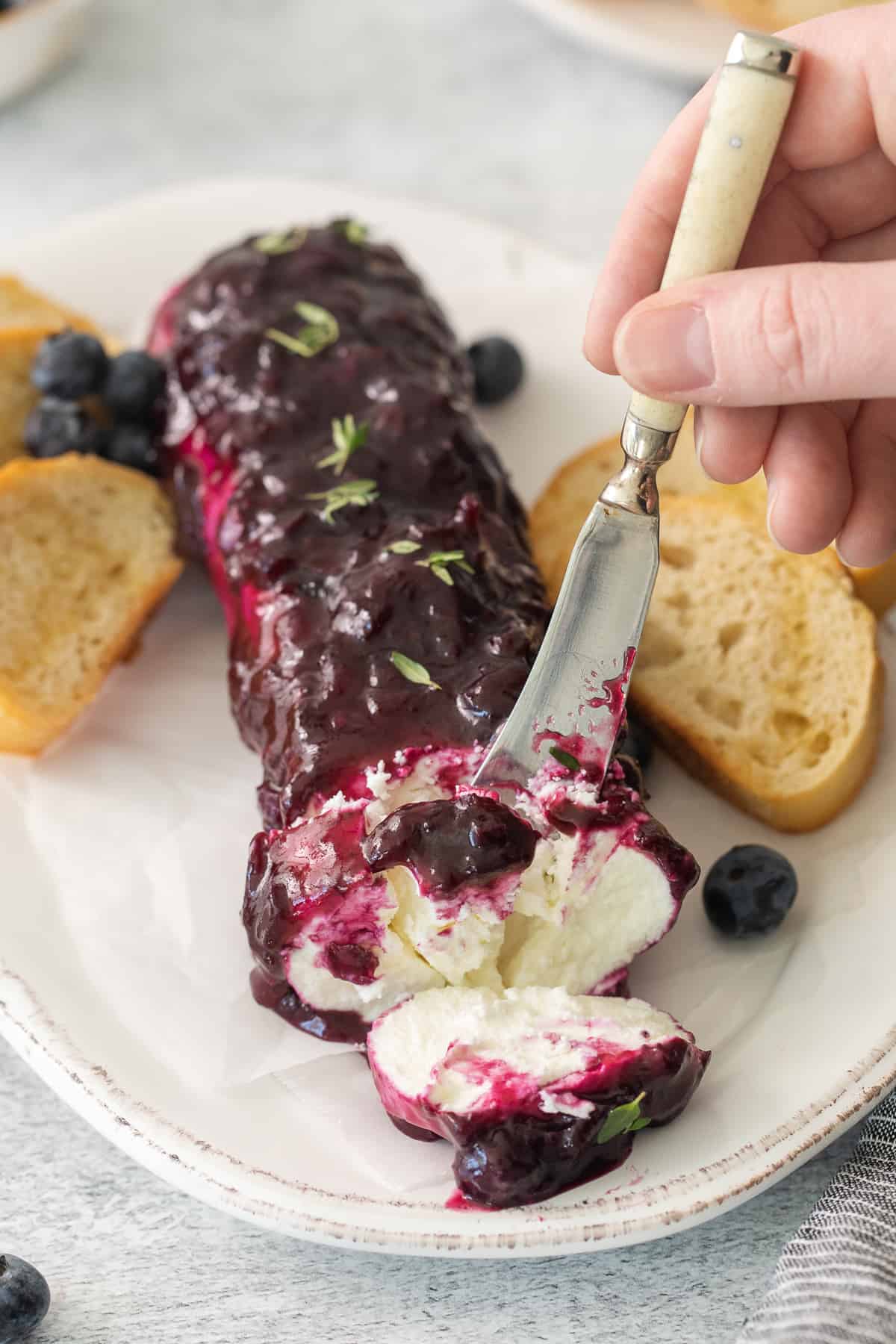 Blueberry got cheese appetizer on a plate with a knife.