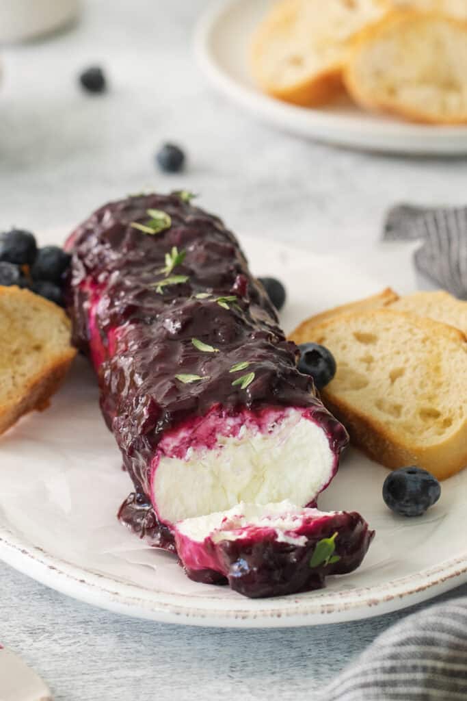 Blueberry goat cheese log on a plate with crostini.