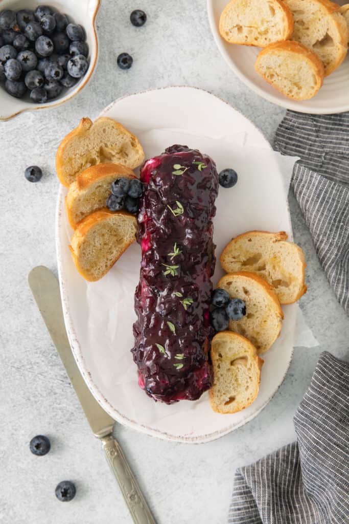 Blueberry goat cheese appetizer on a plate with crostini.
