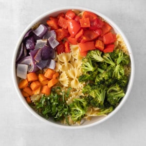 a white bowl filled with pasta and vegetables.