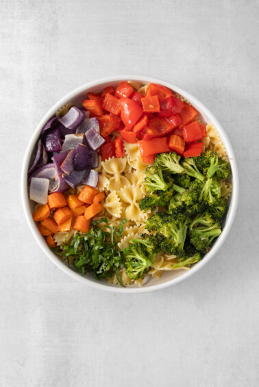 a white bowl filled with pasta and vegetables.