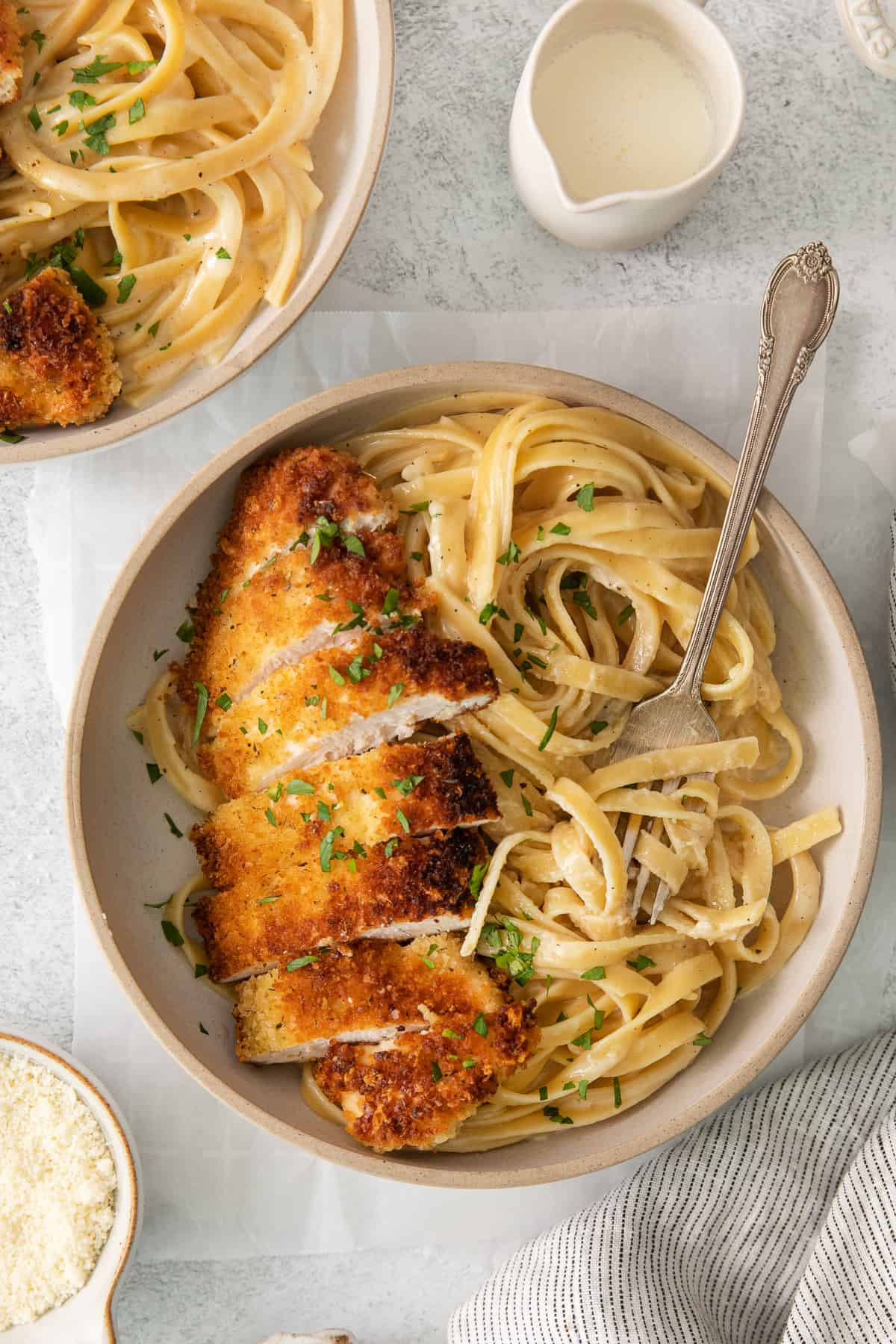 two bowls of pasta with chicken and parmesan.