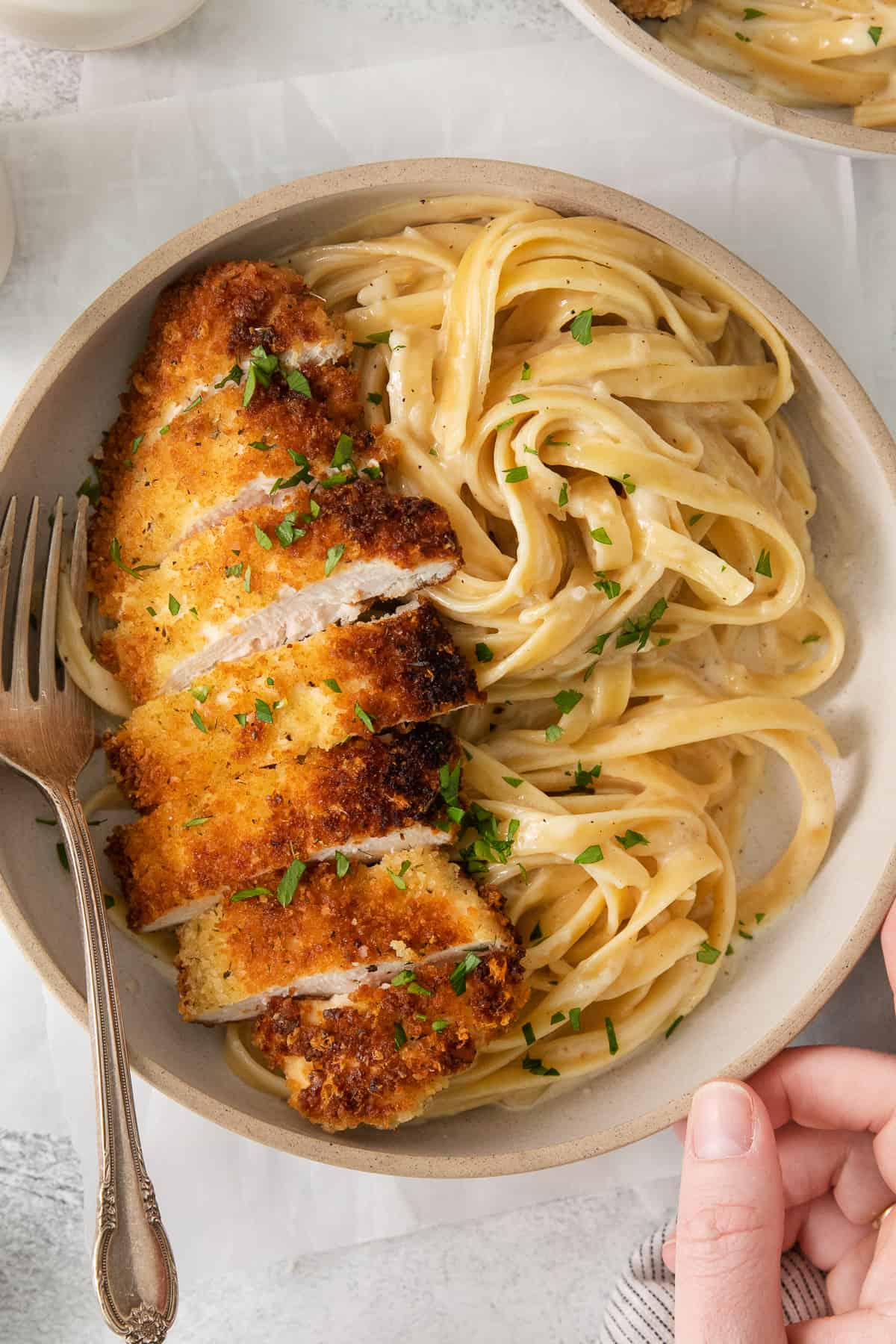 a plate of chicken fettuccine with parmesan cheese and parsley.