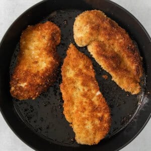 fried chicken in a skillet on a white surface.