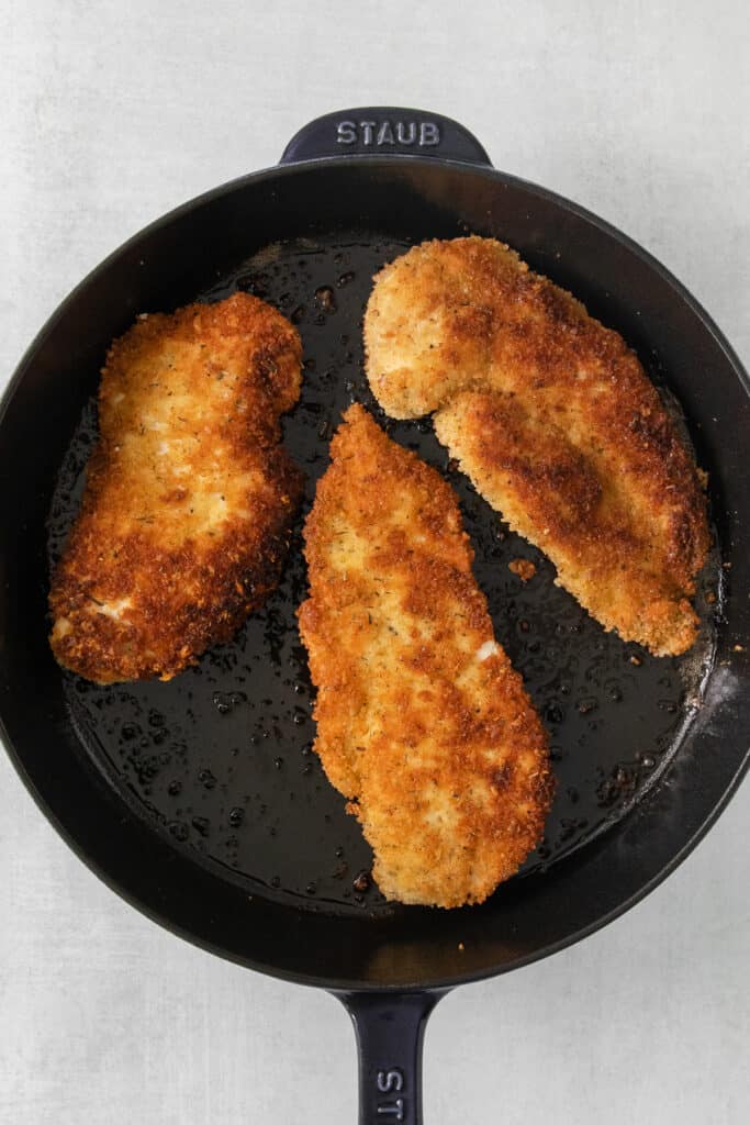 fried chicken in a skillet on a white surface.