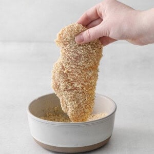 a hand is holding a bowl of sesame seeds.