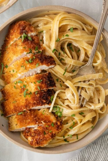 chicken parmigiana in a bowl with pasta and parmesan.
