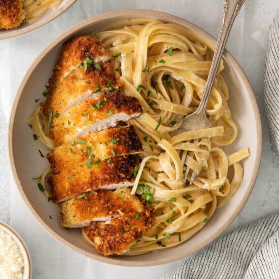 chicken parmigiana in a bowl with pasta and parmesan.