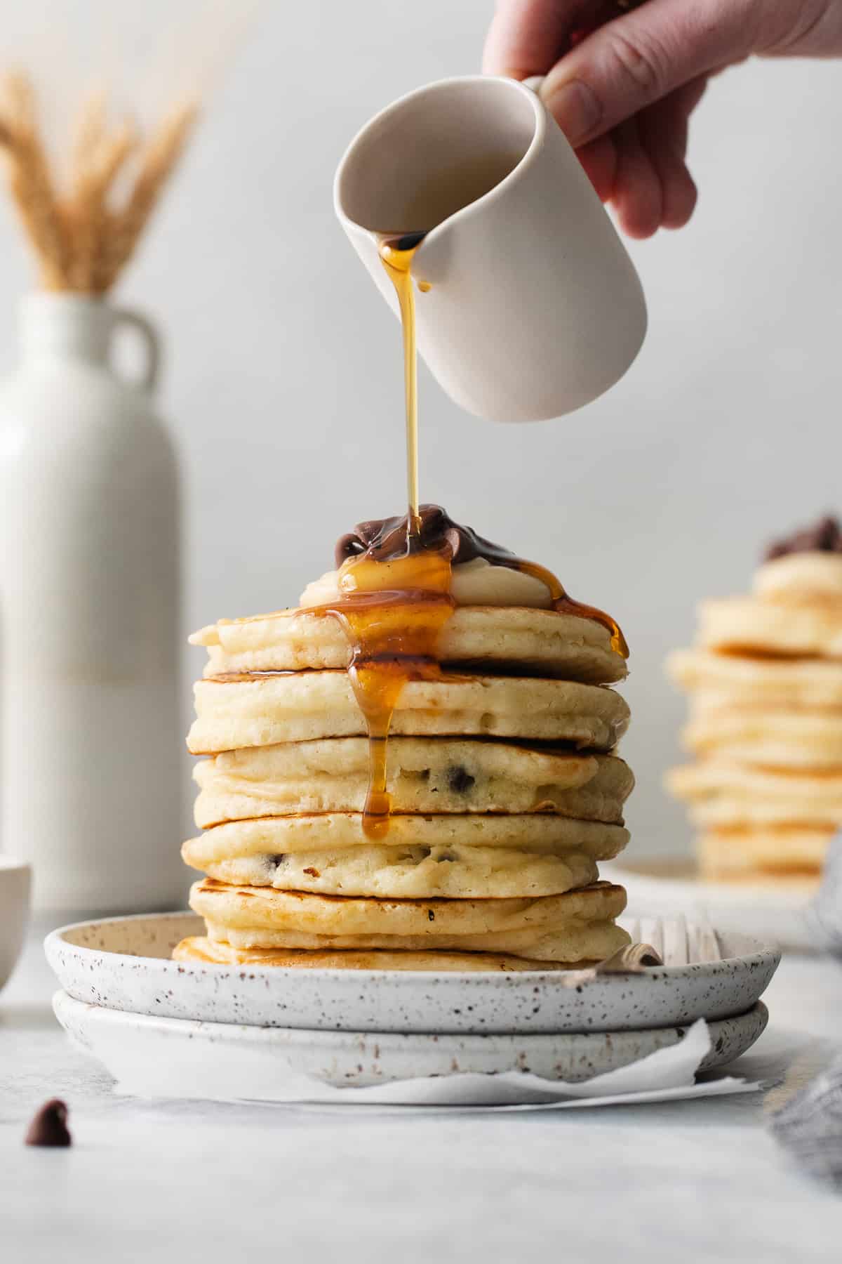 Cream cheese stuffed pancakes on a plate topped with maple syrup.