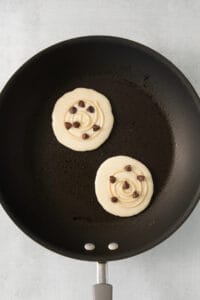 two pancakes in a frying pan with chocolate chips.
