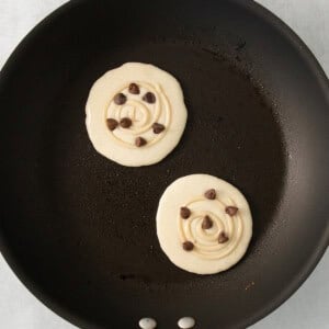 two pancakes in a frying pan with chocolate chips.