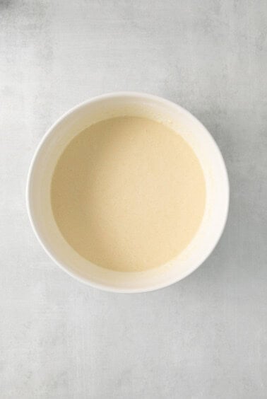 a white bowl with a yellow liquid in it.