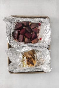 roasted beets in foil on a table.