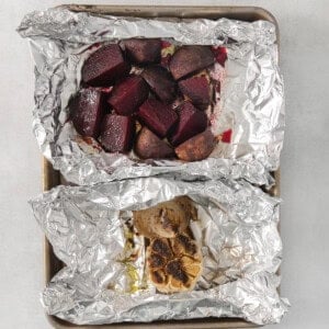 roasted beets in foil on a table.