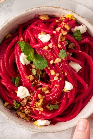 a bowl of beet noodles with feta cheese and walnuts.