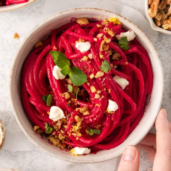 a bowl of beet noodles with feta cheese and walnuts.