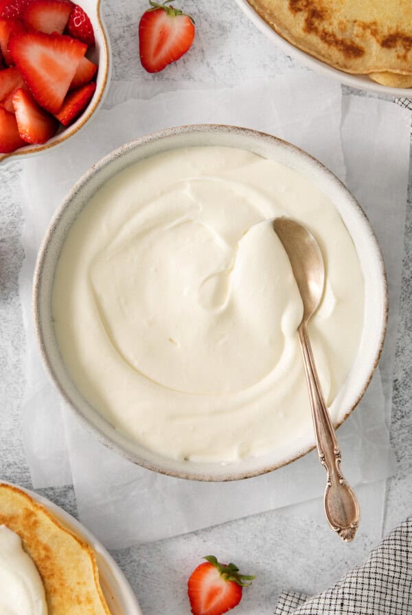 a plate of pancakes with whipped cream and strawberries.