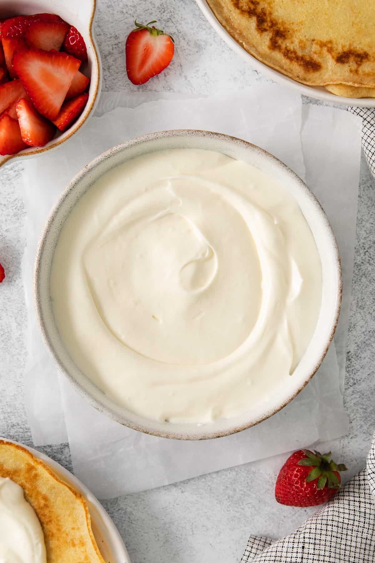 a plate of pancakes with whipped cream and strawberries.