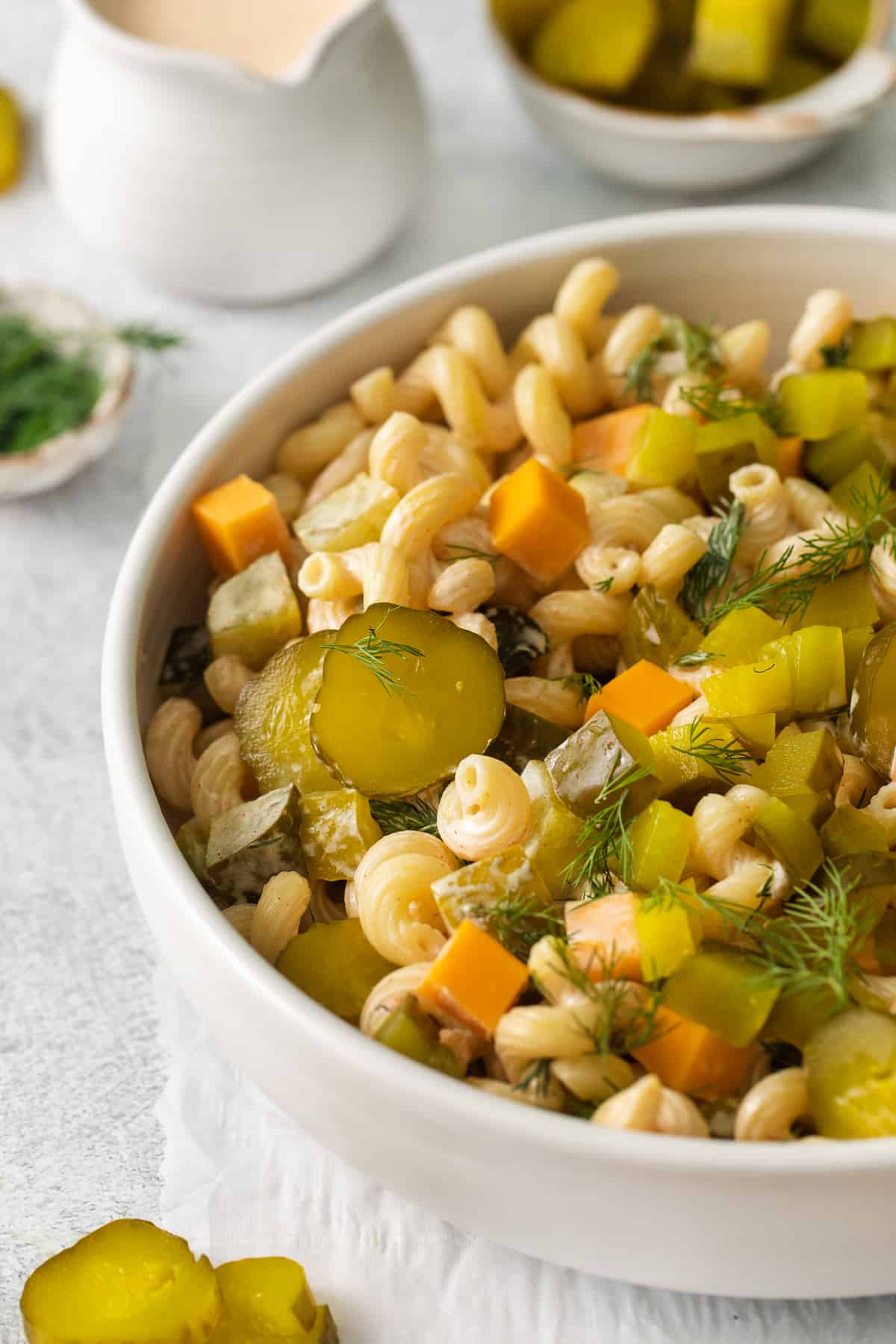 Dill pickle pasta salad in a bowl topped with sliced pickles.