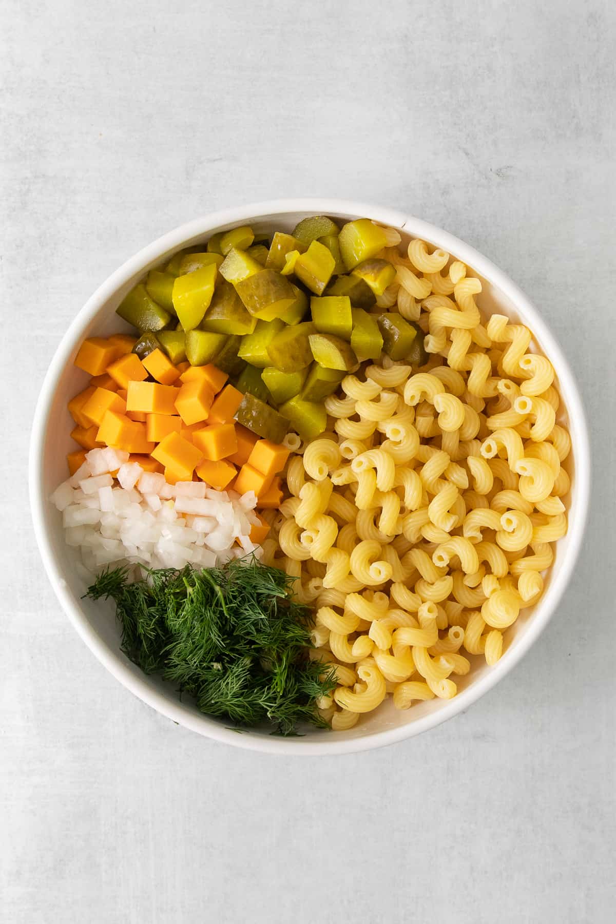 Dill pickle pasta salad ingredients in a large serving bowl.