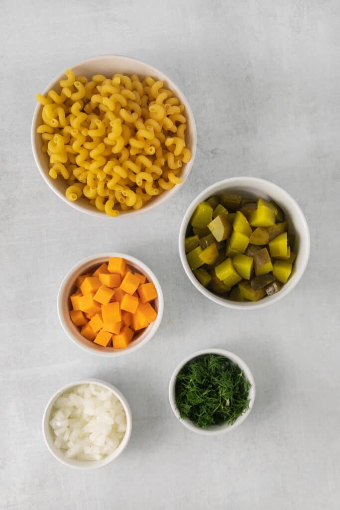 Ingredients for dill pickle pasta salad in bowls.