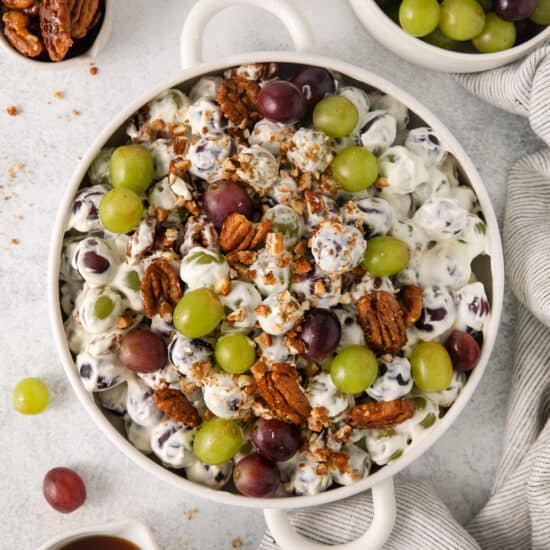 Grape salad in a bowl topped with candied pecans.