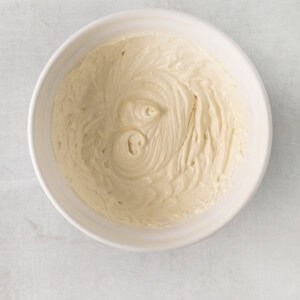 whipped cream in a white bowl on a white surface.