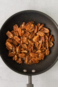 pecans in a frying pan on a white background.