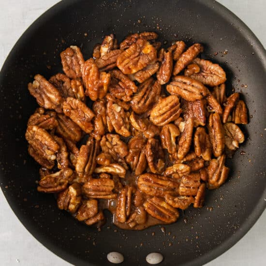 pecans in a frying pan on a white background.
