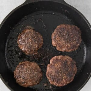 beef burgers in a cast iron skillet.