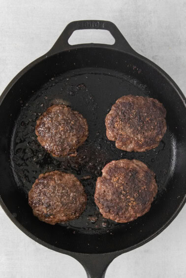 beef burgers in a cast iron skillet.