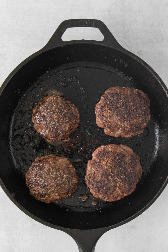 Juicy lucy burgers in a cast iron skillet.