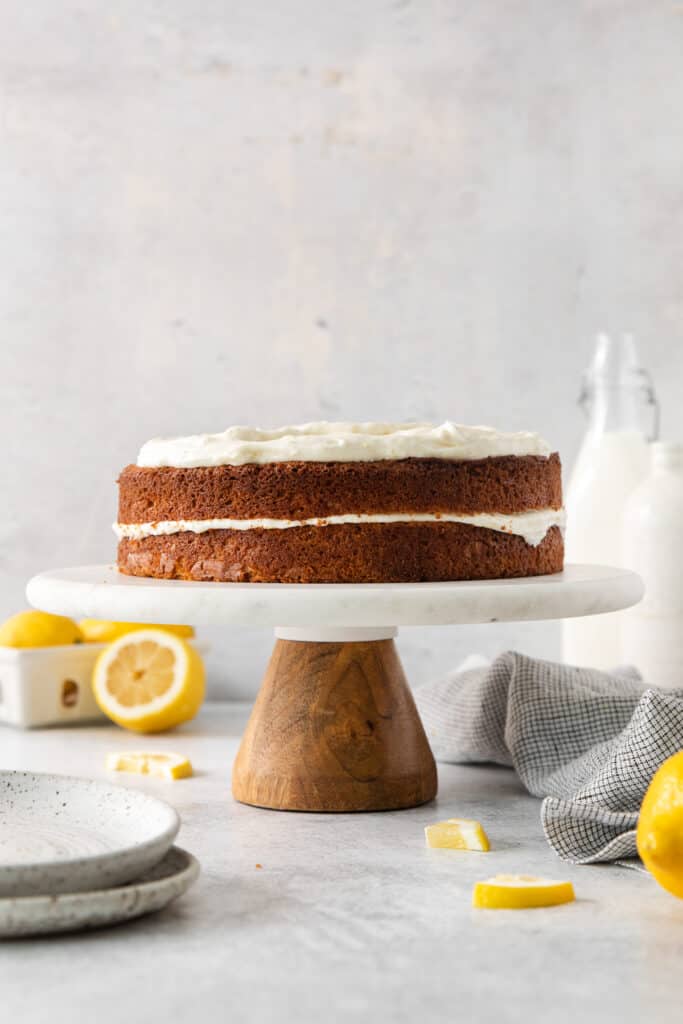 Two layer lemon olive oil cake on a cake stand.