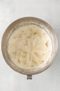 whipped cream in a metal bowl on a white background.