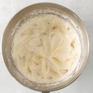 whipped cream in a metal bowl on a white background.