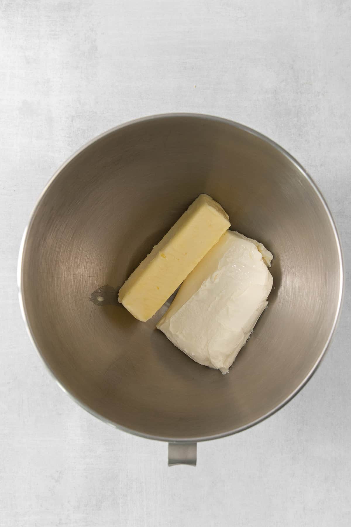 This lemon cream cheese frosting is the perfect compliment to your summertime desserts! The rich frosting gets balanced out with a delicious bright lemon flavor made from fresh lemons. Cream cheese and butter in a bowl.