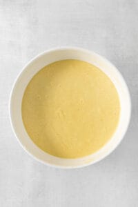 a bowl of yellow batter on a white surface.